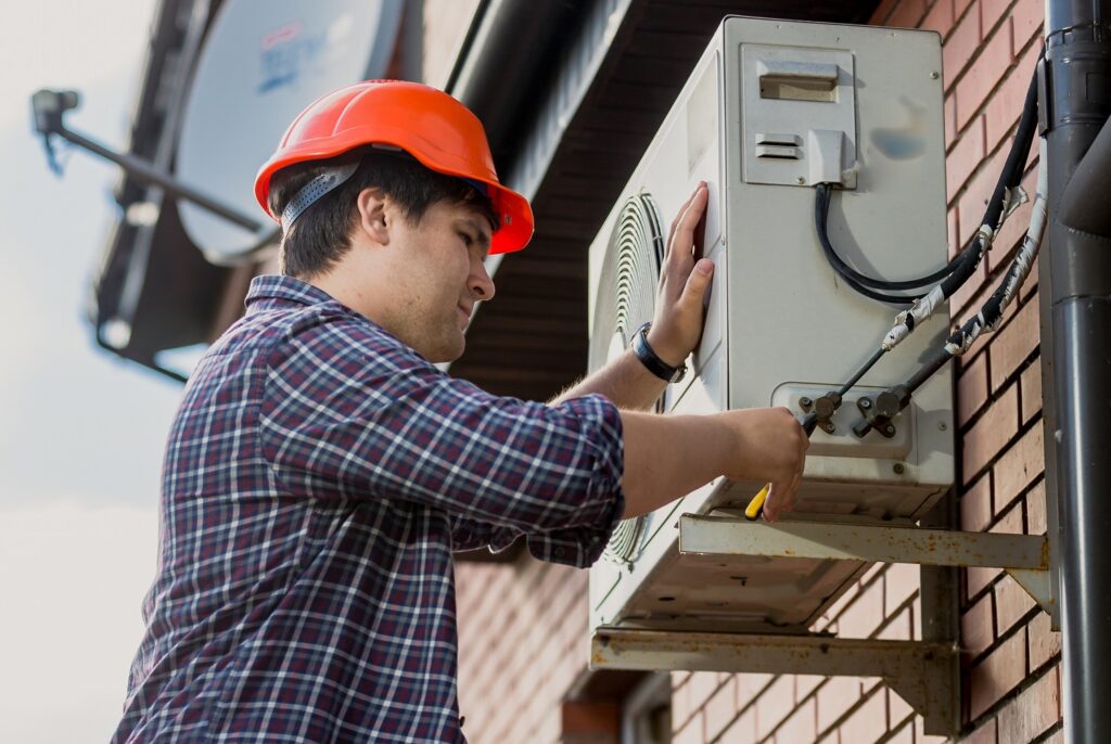 A man with red cap installing a Heat pump, focus on his work and profession