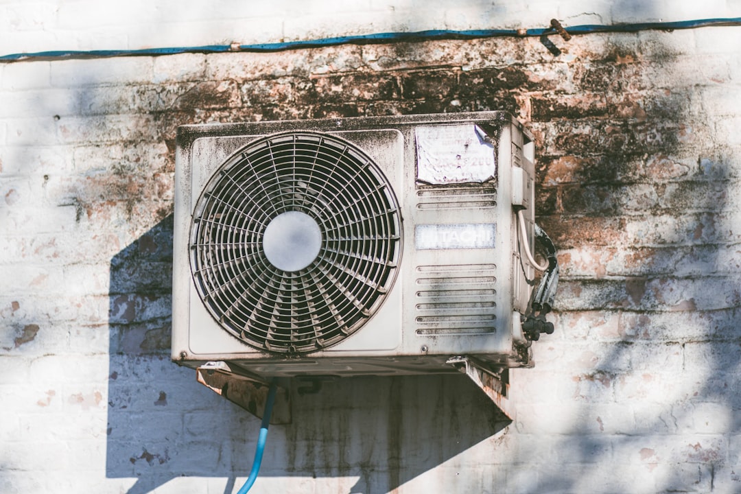 AC tune-up technician inspecting outdoor condenser unit in Des Moines suburban backyard - how often should you schedule an